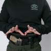 A man dressed in a black Durable Concealment Hoodie lifts his layers to reveal a pistol and spare magazine holstered at the waist using a tactical belt, demonstrating effective concealed carry layering