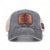 Front-facing view of gray trucker cap with brown leather FNH Firearms patch centered on front panel.